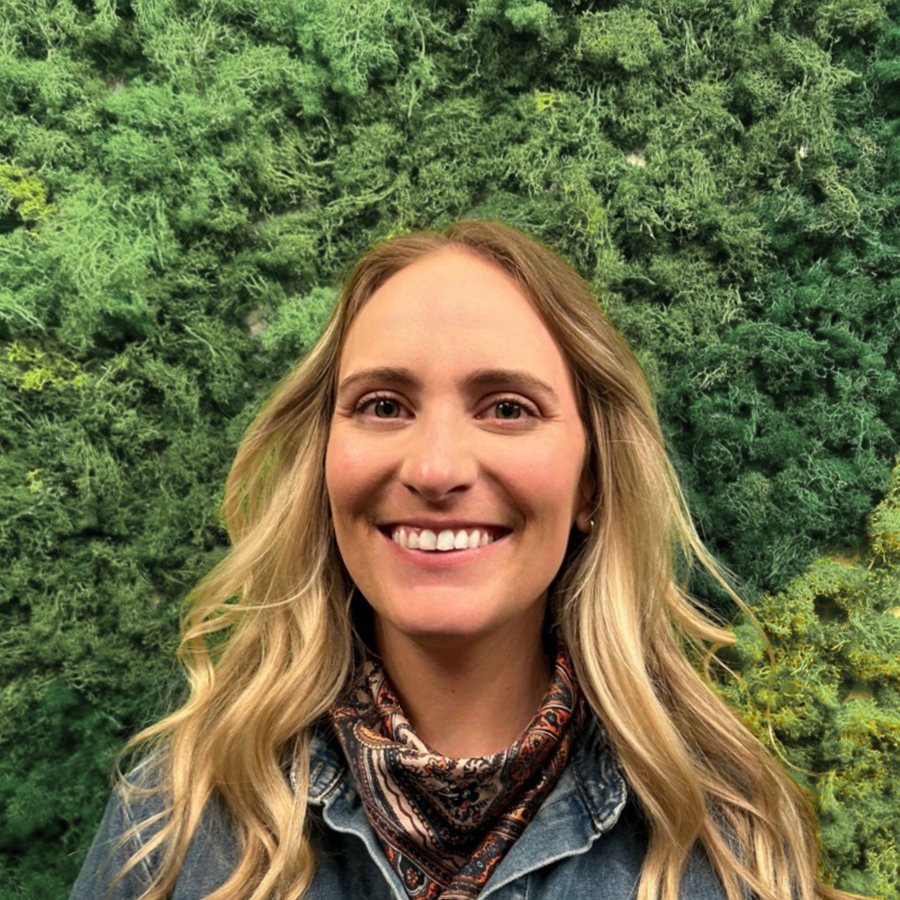Carly, founder of untangle&simplify, smiling in front of a living moss wall